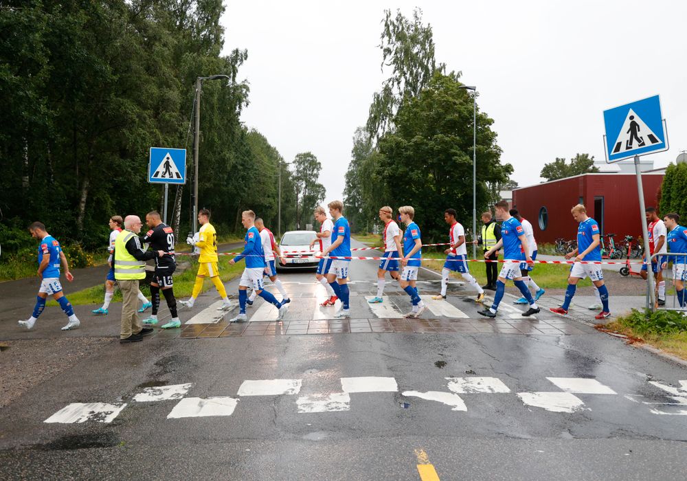KFUM Oslo- og Ranheim-spillere krysser bilvei for å komme seg til KFUM Oslos hjemmebane, KFUM Arena.