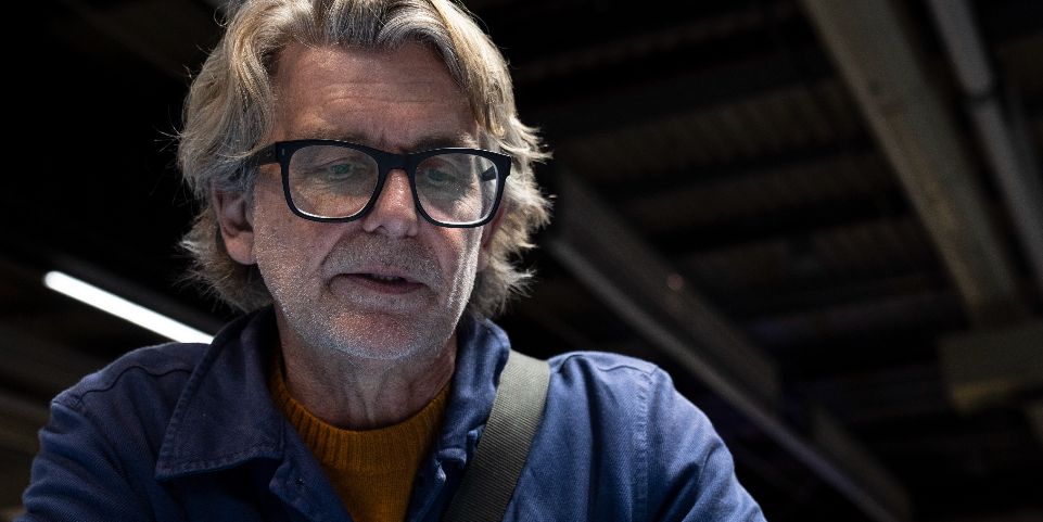 Ulf Dalnäs, en man i blå skjorta, sitter vid ett blått bord.