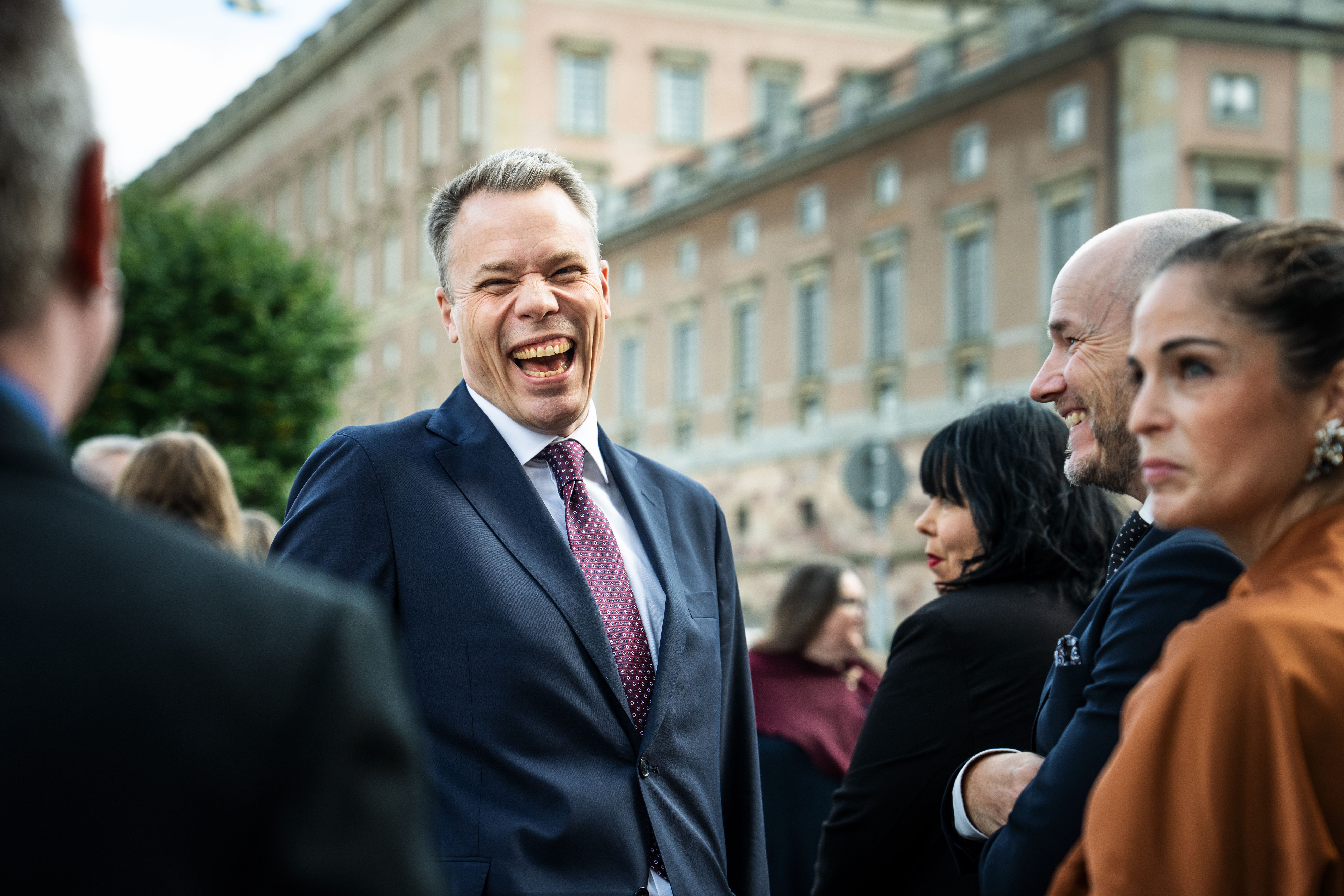 V-toppen Daniel Bernmar från Göteborg utanför riksdagen. Han har på sig mörk kostym och skrattar med hela ansiktet åt något en kollega säger.