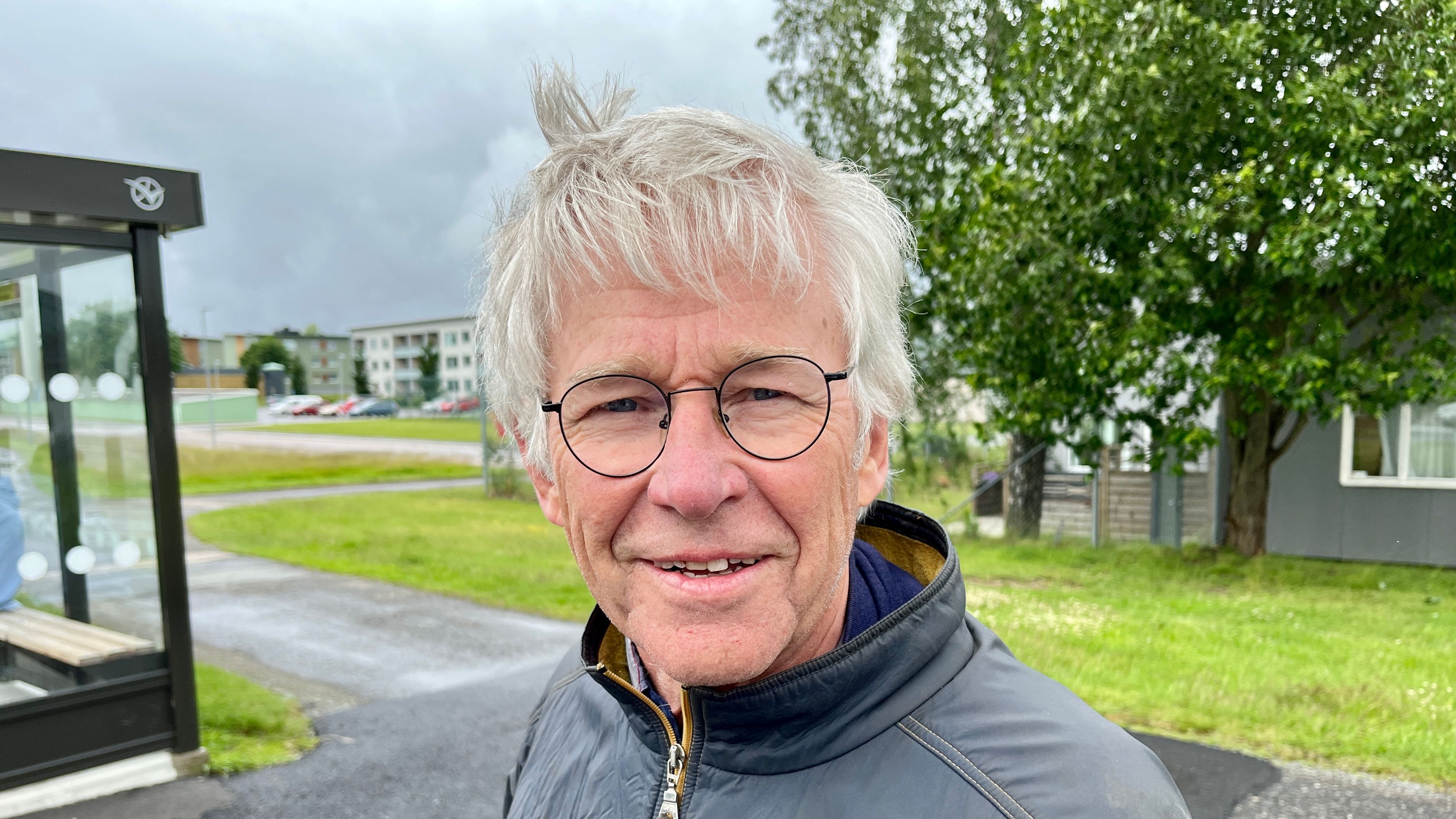 En leende gråhårig man vid busskur
